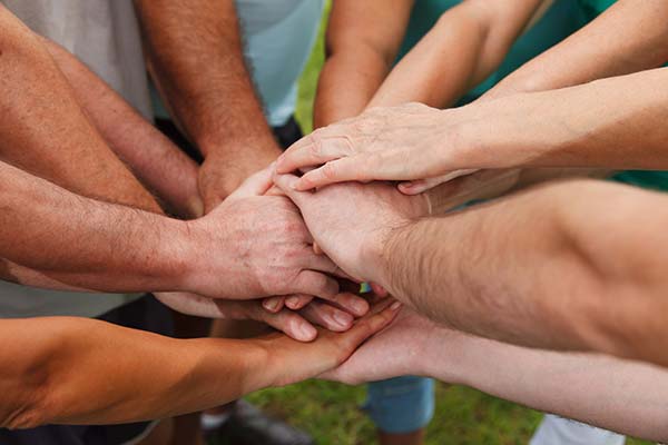 group of people putting their hands in a circle